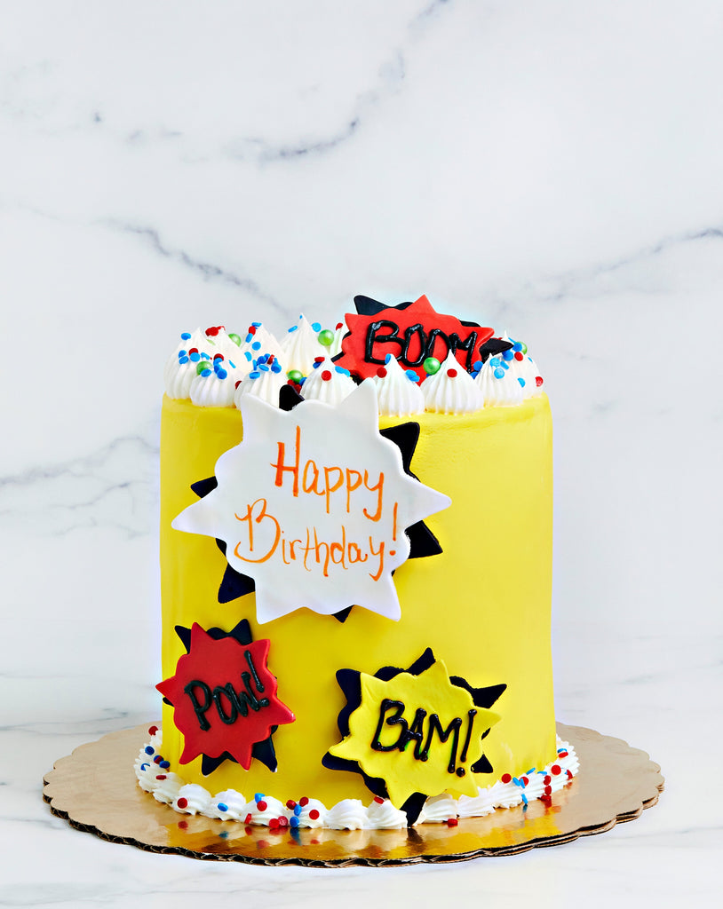 Yellow cake with superhero captions: Pow! Bam!