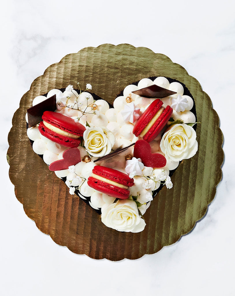 Top view of heart shaped naked cake with macaroons and roses on the top