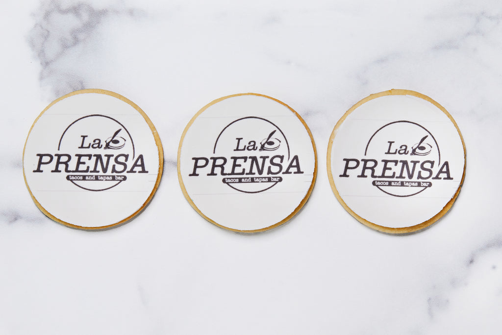 Three sugar cookies with La Prensa logo printed in frosting