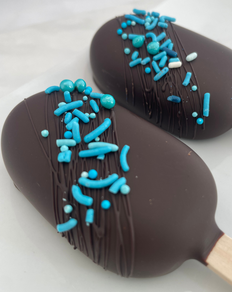 Two chocolate cakesicles with blue sprinkles