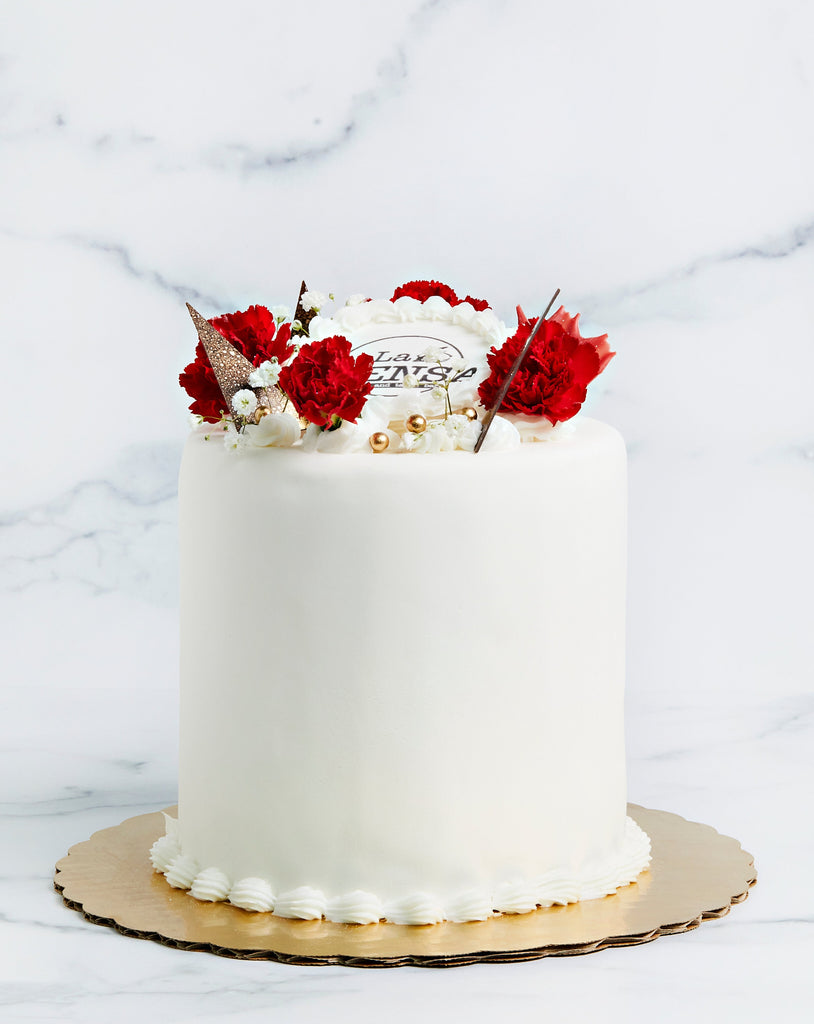 White cake with fresh flowers and custom edible logo