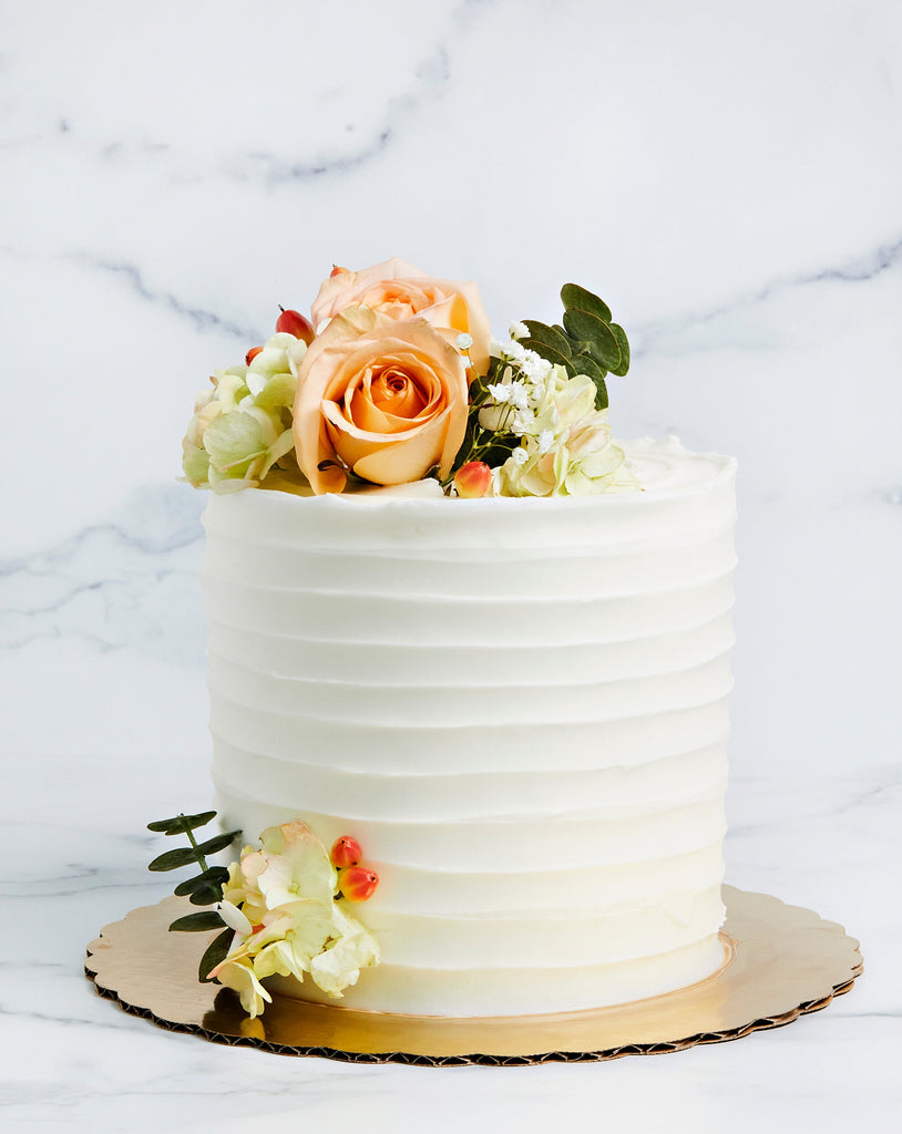 Striped buttercream frosted cake with flowers on top