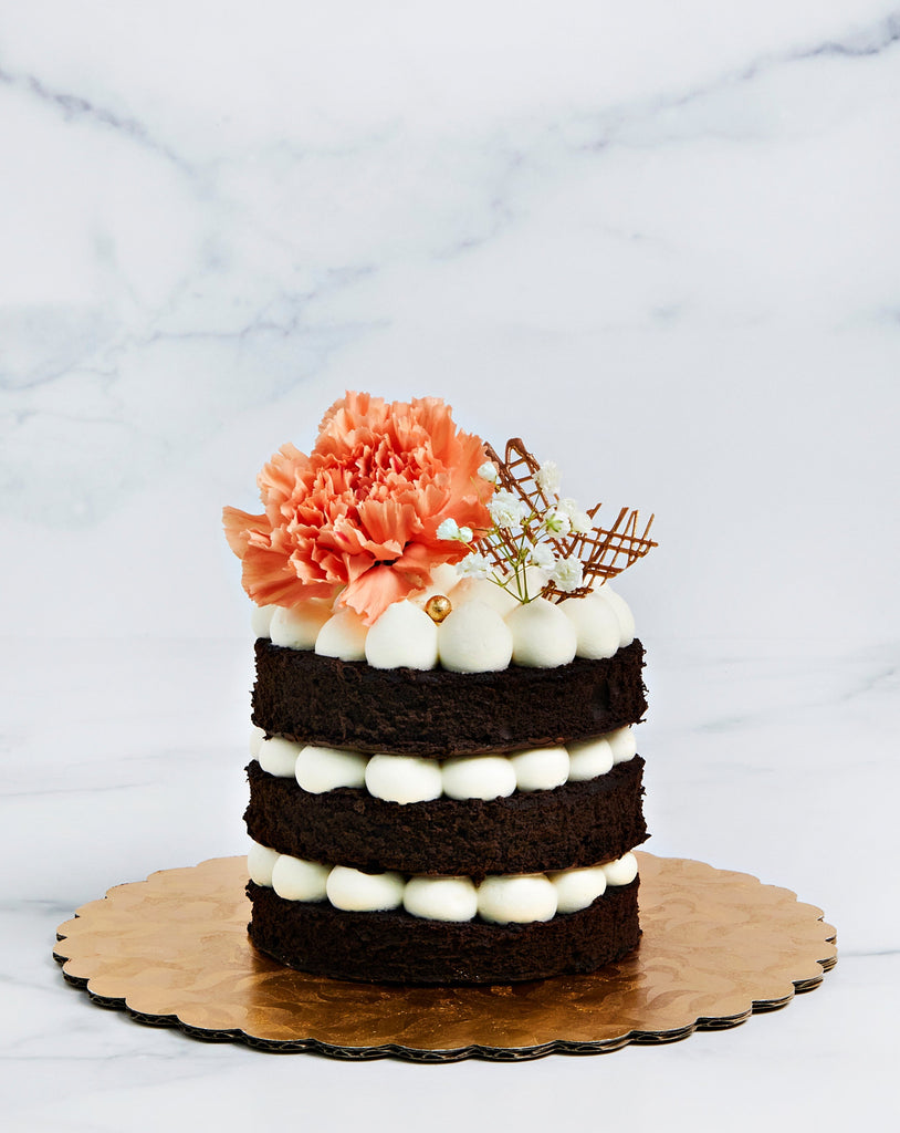 Open layer cake with center frosting exposes, and large flower on top.